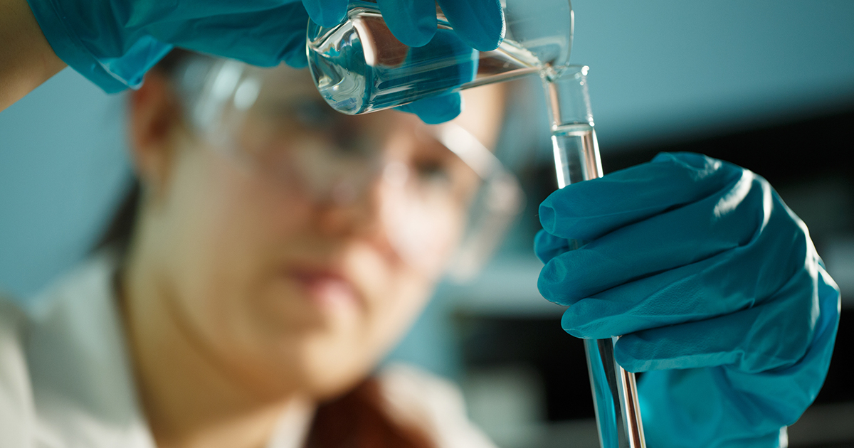 Photo of lab assistant conducting chemical tests with tubes at table